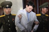 Otto Warmbier is handcuffed and being led by two North Korean soldiers