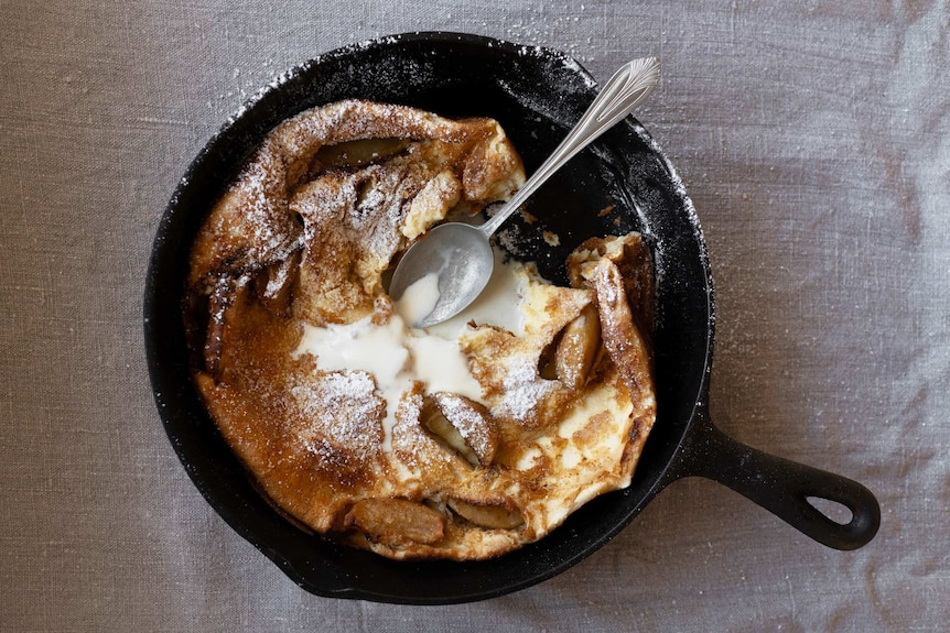 A baked Dutch baby style pancake with apple, cinnamon and topped with icing sugar and cream, an easy pancake recipe.