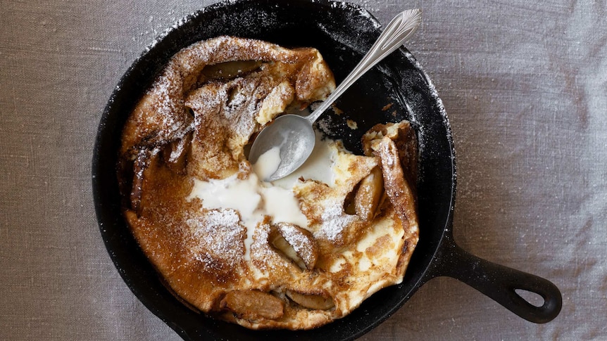 A baked Dutch baby style pancake with apple, cinnamon and topped with icing sugar and cream, an easy pancake recipe.