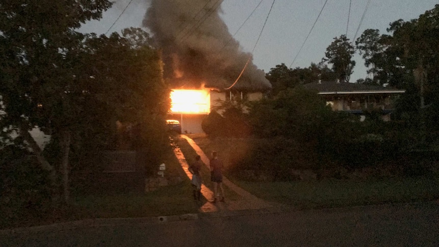 Neighbours stand outside an Everton Hills home fully engulfed in flames, a fire that killed three people.