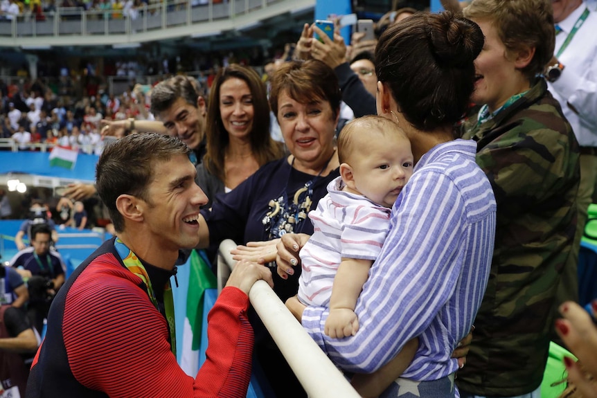Michael Phelps smiles at his family, including baby Boomer, after winning his 20th Olympic gold medal