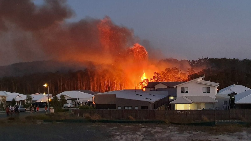 A bushfire flares close to suburban houses