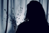 Silhouette of woman in darkness, speaking to the ABC.