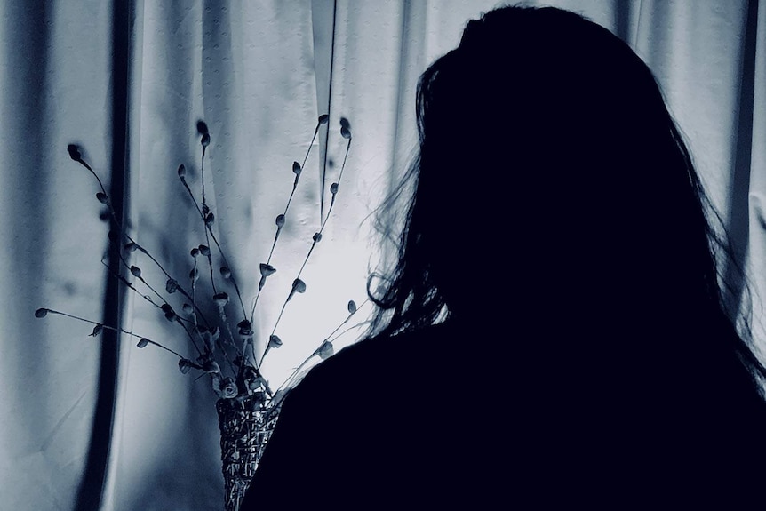 Silhouette of woman in darkness, speaking to the ABC.