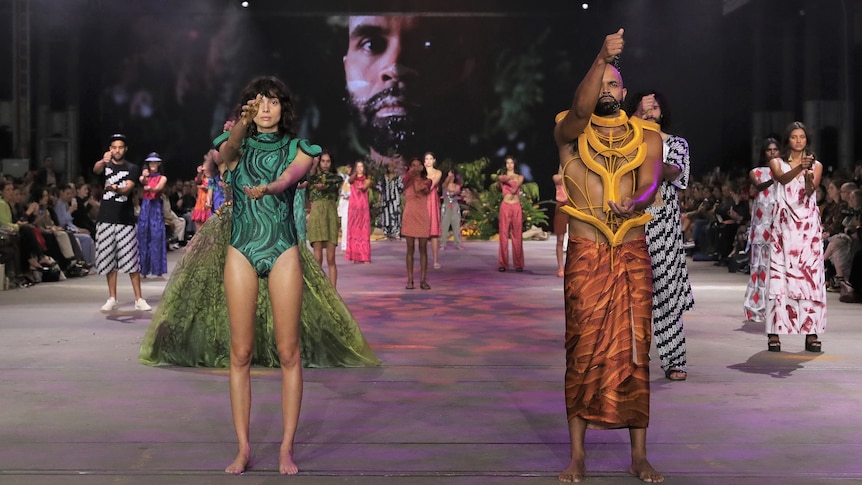 Indigenous models wear brightly coloured designs on a fashion runway in Sydney.