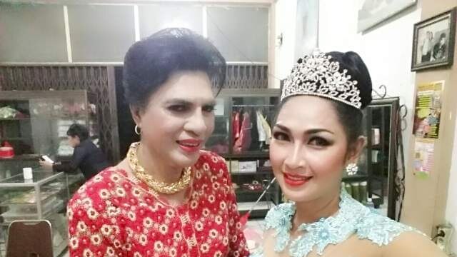 Mommy Yuli wears a red dress, next to a friend who is wearing a blue formal dress and a tiara.