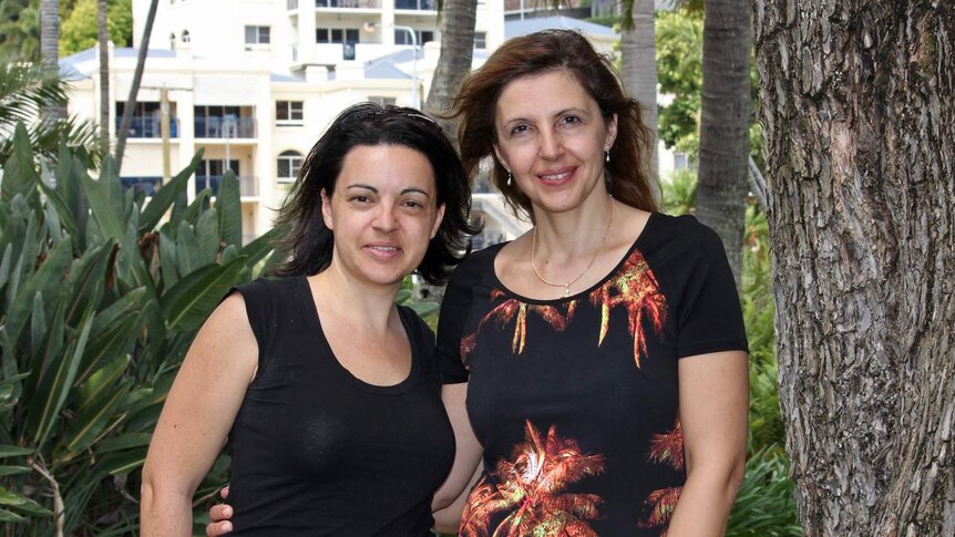 Two women embrace as friends in a garden in Townsville