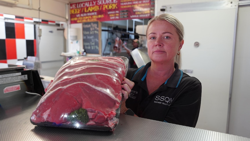 A woman holding a tray of steaks