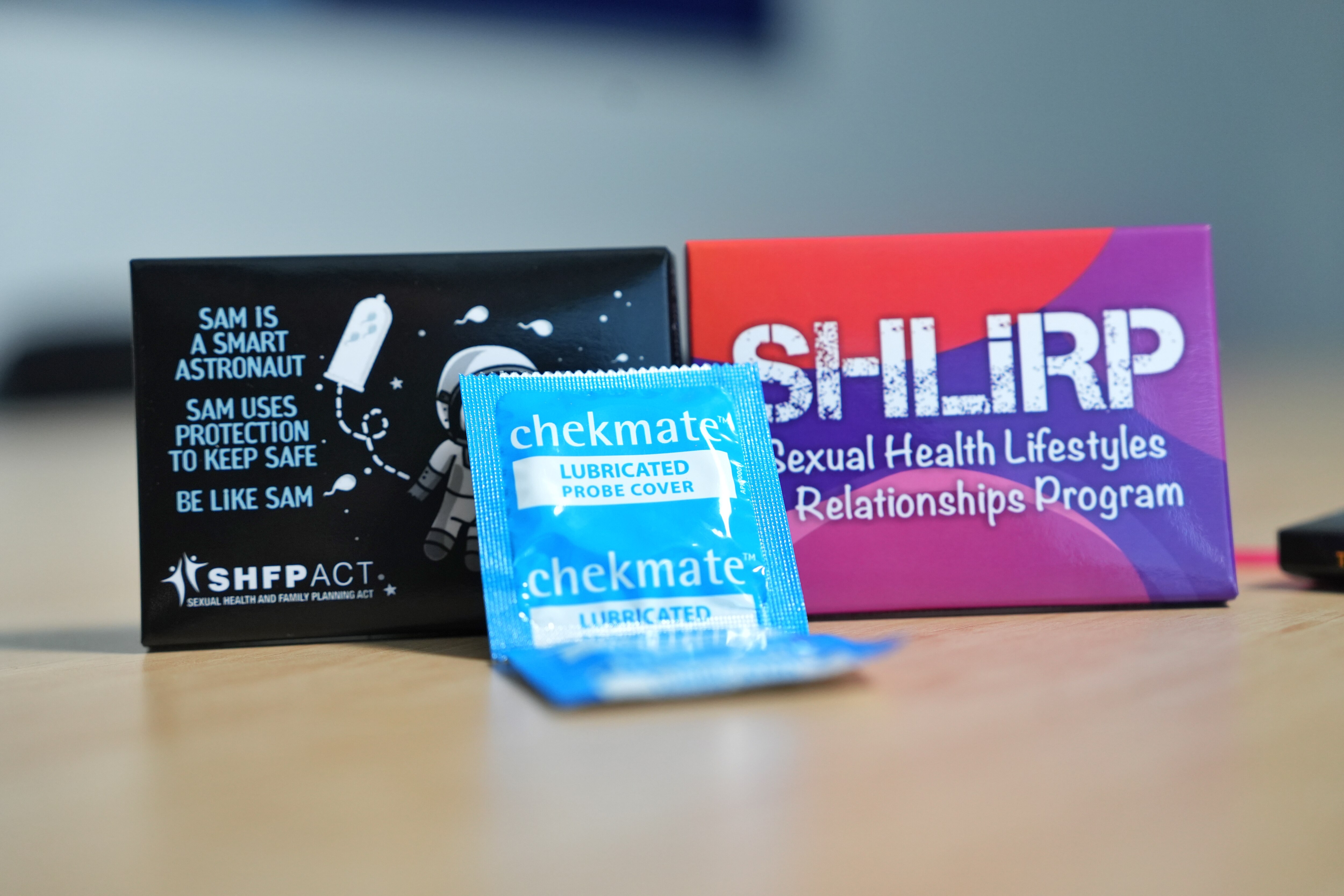 Two credit card sized boxes with sexual health organisation logos, with an ultrasound probe cover in front.