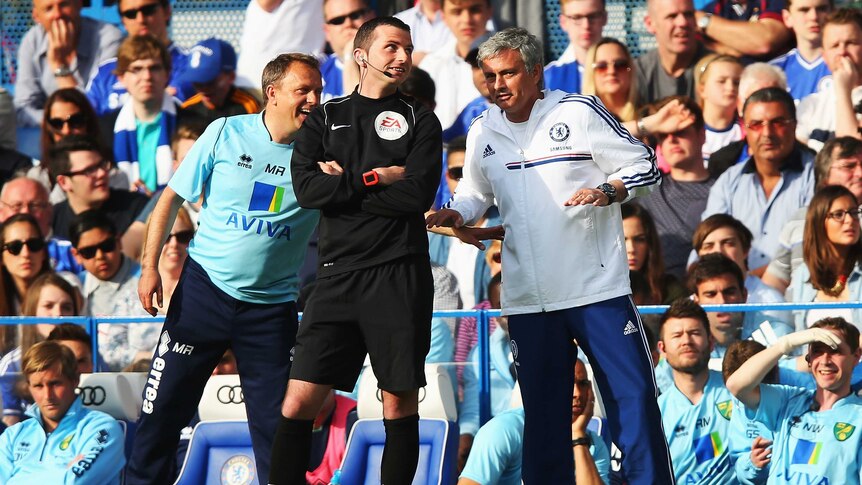 Chelsea manager Jose Mourinho (R) and Norwich's Neil Adams (L) talk to the fourth official.