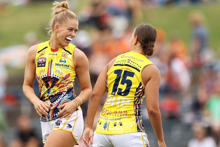 Two Adelaide Crows AFLW players celebrate a goal against the GWS Giants.