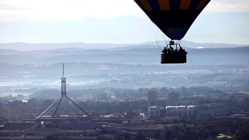 A hot air balloon passes over Parliament House, Canberra.