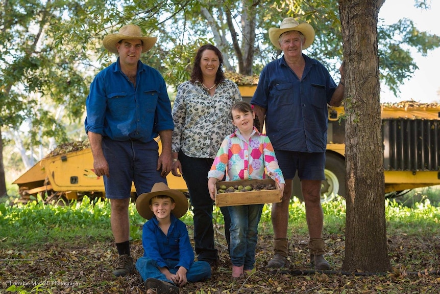 Lindsay Chicken, Michelle Chicken and Boyd Paton stand behind seated Drew Paton and Caitlyn Paton who holds a box of pecans.