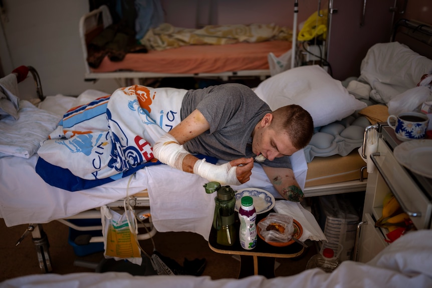 Young man rolled over to feed himself from a bedside tray