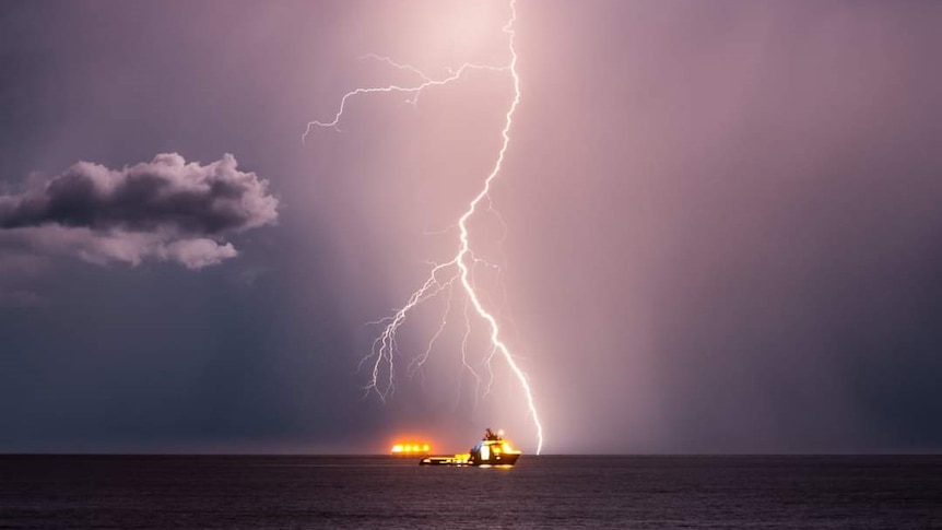 A bolt of lightning strikes over a ship in the ocean