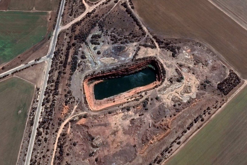 Satellite image of the dam with some water in it and brown fields around about it.