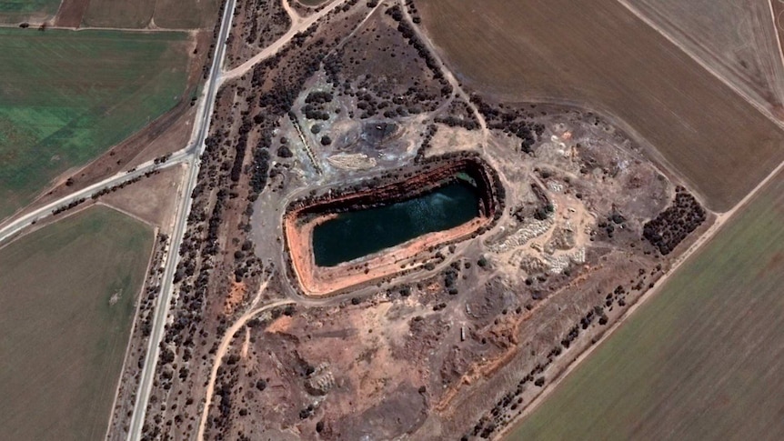 Satellite image of the dam with some water in it and brown fields around about it.