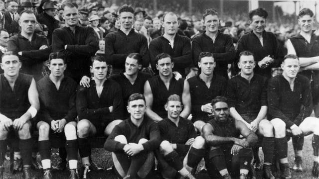 A black and white pic of the AFL team standing and kneeling for a team photo. 