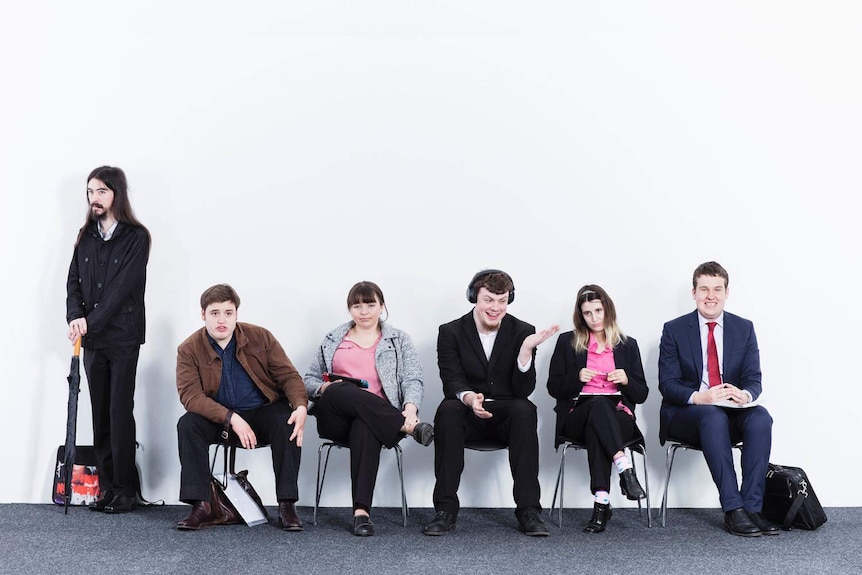 Six people line up as if preparing for a job interview