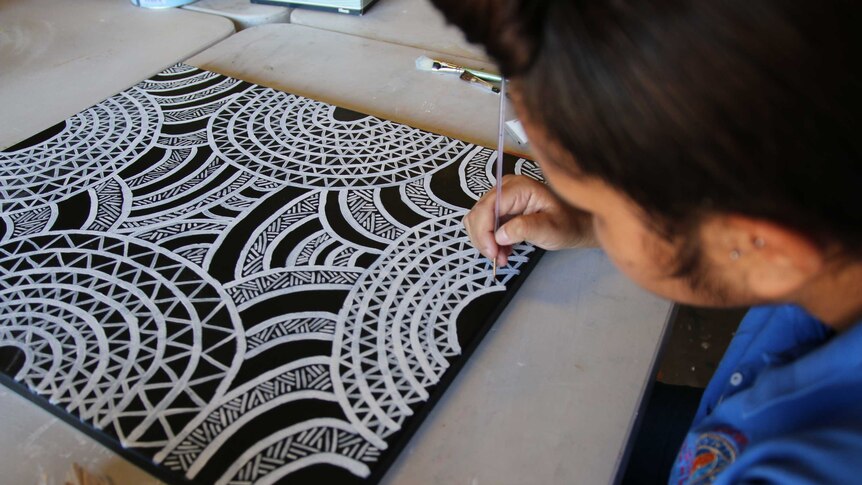 A woman paints at the Gomeroi gaaynggal arts studio.