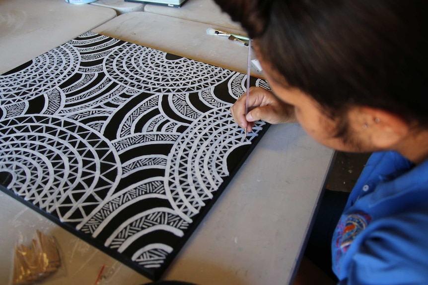 A woman paints at the Gomeroi gaaynggal arts studio.