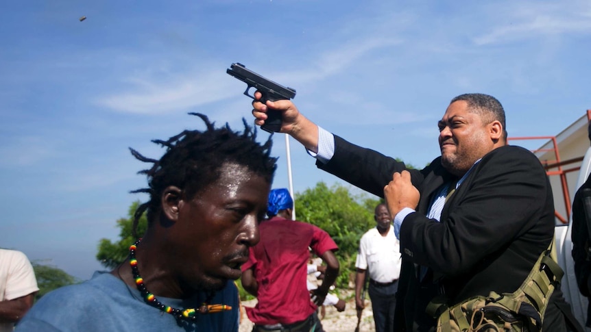Ralph Fethiere steps out of a car pointing his gun in the air, as protesters scramble