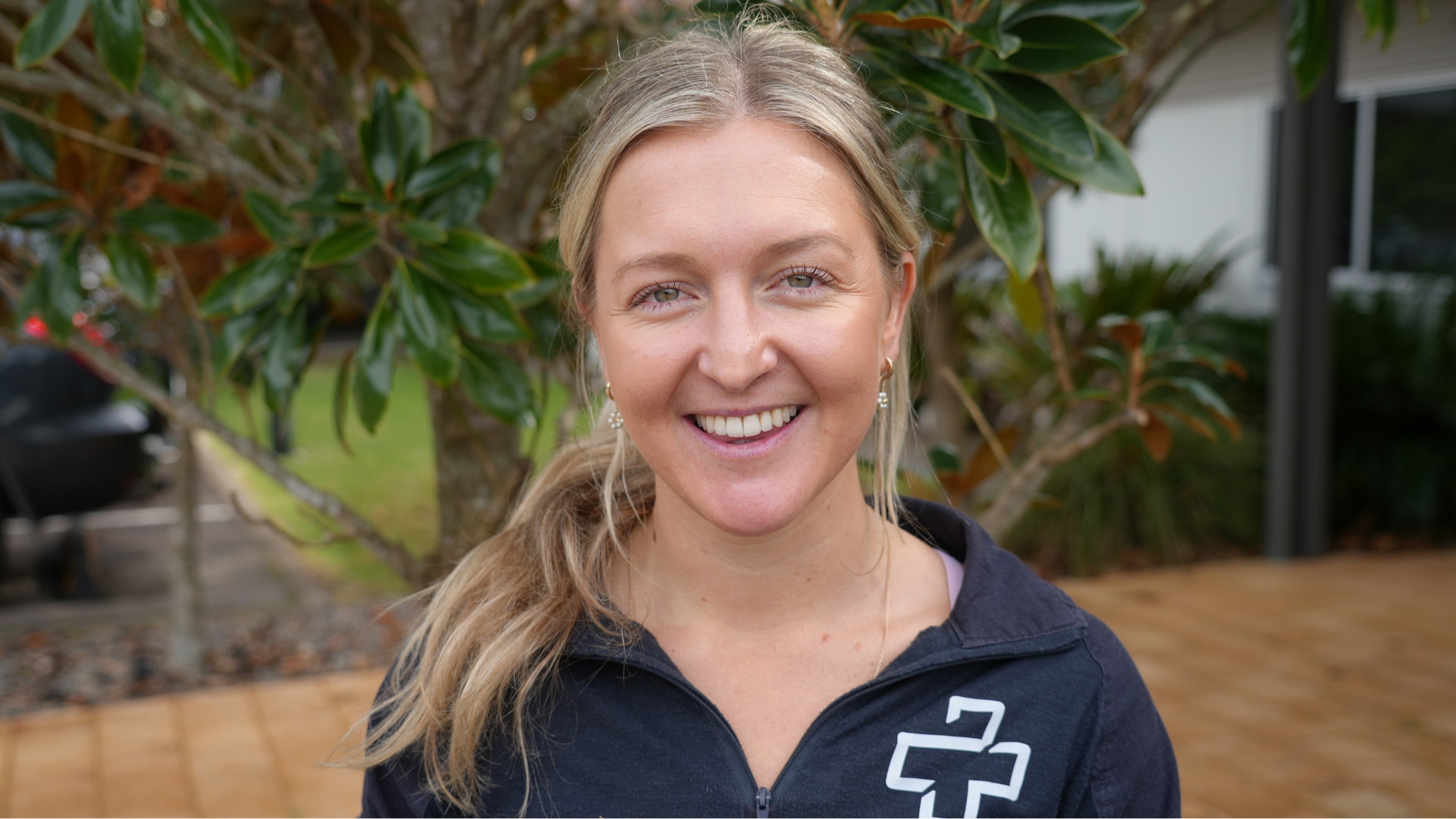A blonde woman standing outside and smiling at the camera