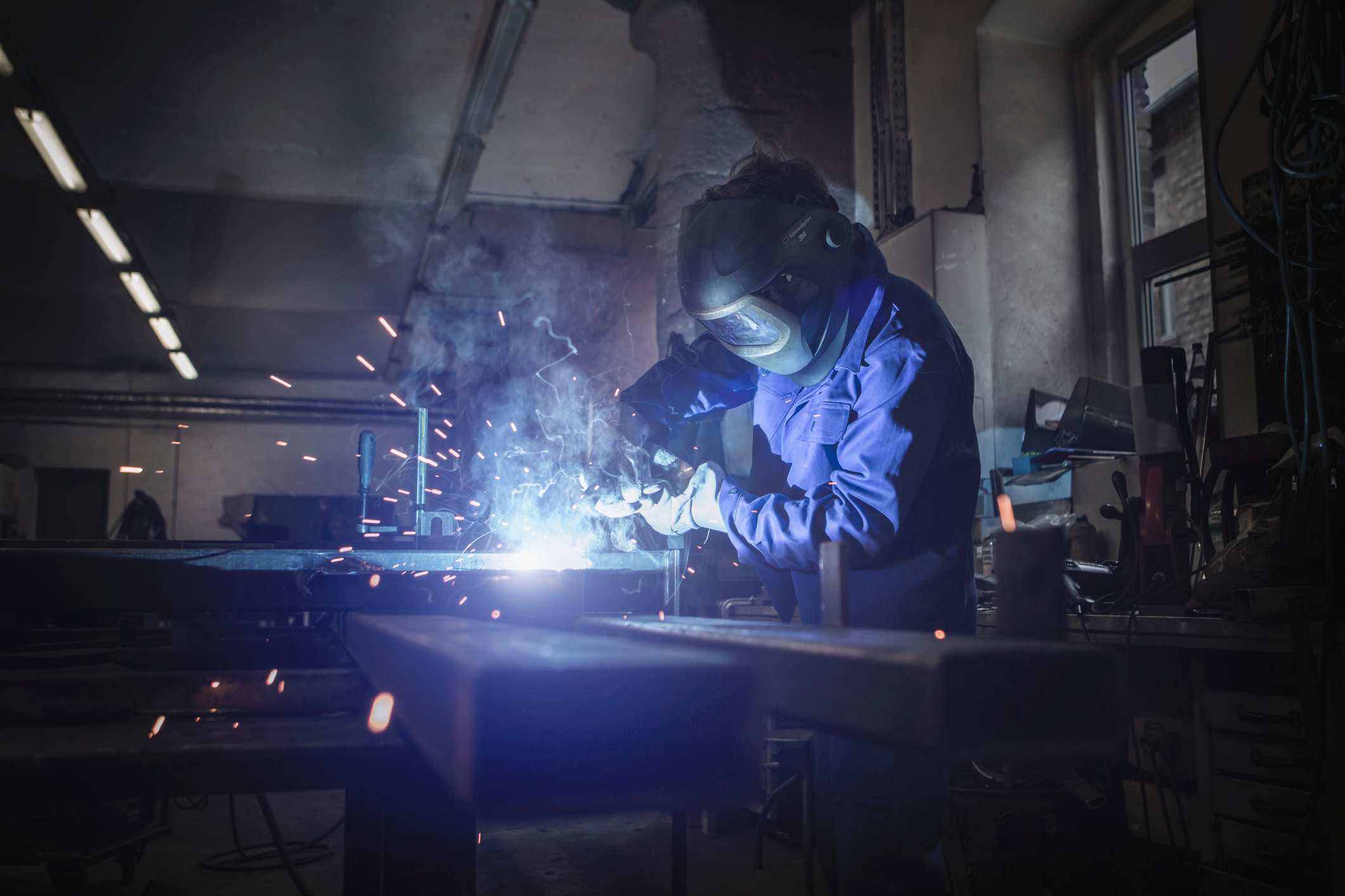 A person wearing a mask cutting metal with machinery