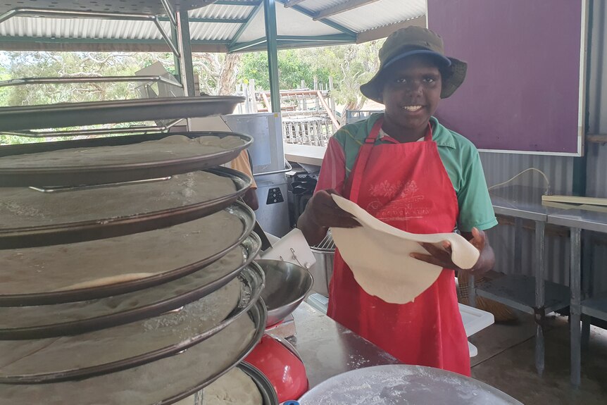 Student holding a pizza base in his hands