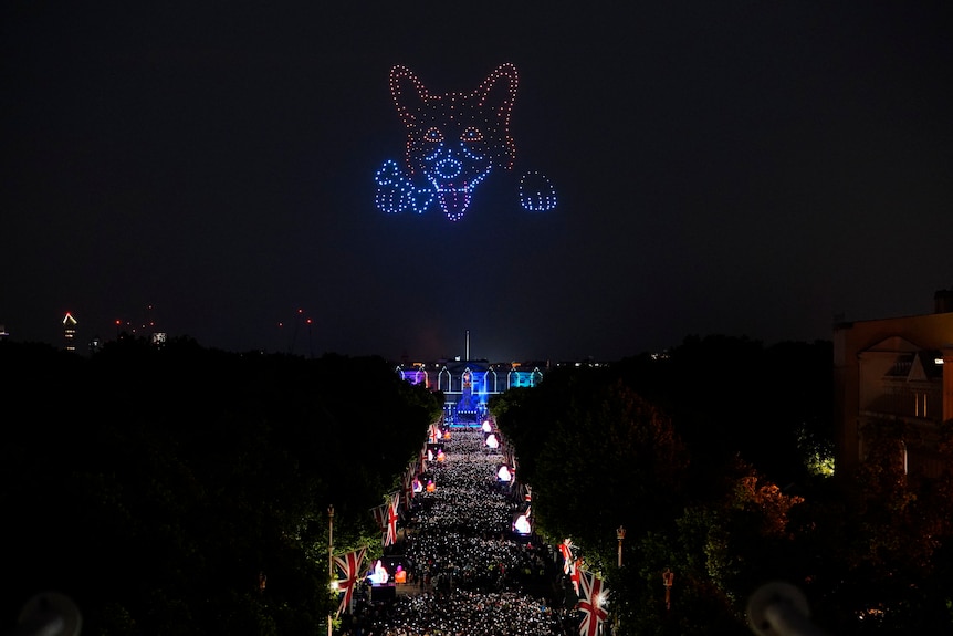 I droni con luci blu e rosse creano una figura di corgi felice sopra Buckingham Palace.