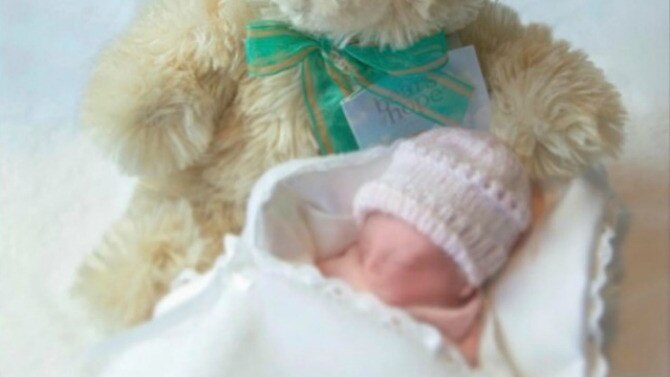A stillborn baby rests with a teddy bear