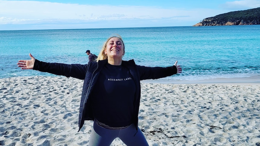 Hannah smiles while standing on a beach.