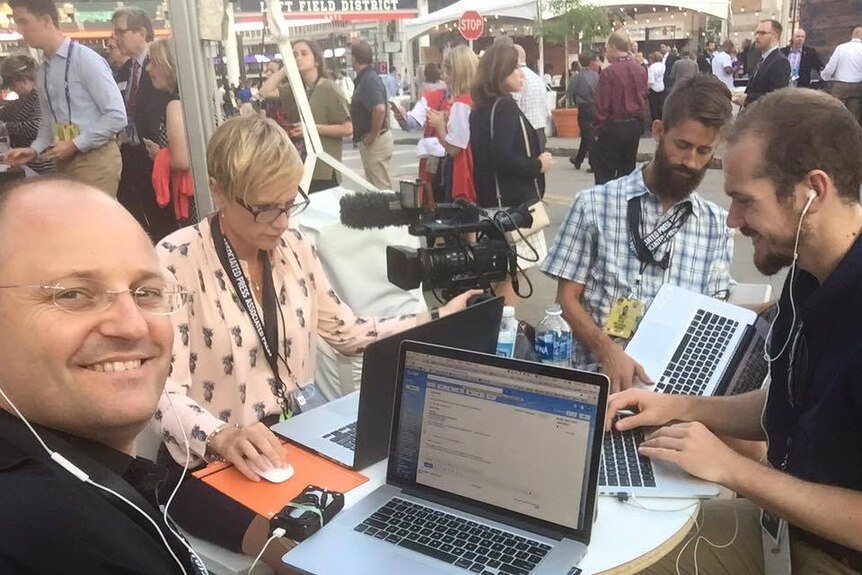 ABC team sitting at table on laptops with camera.