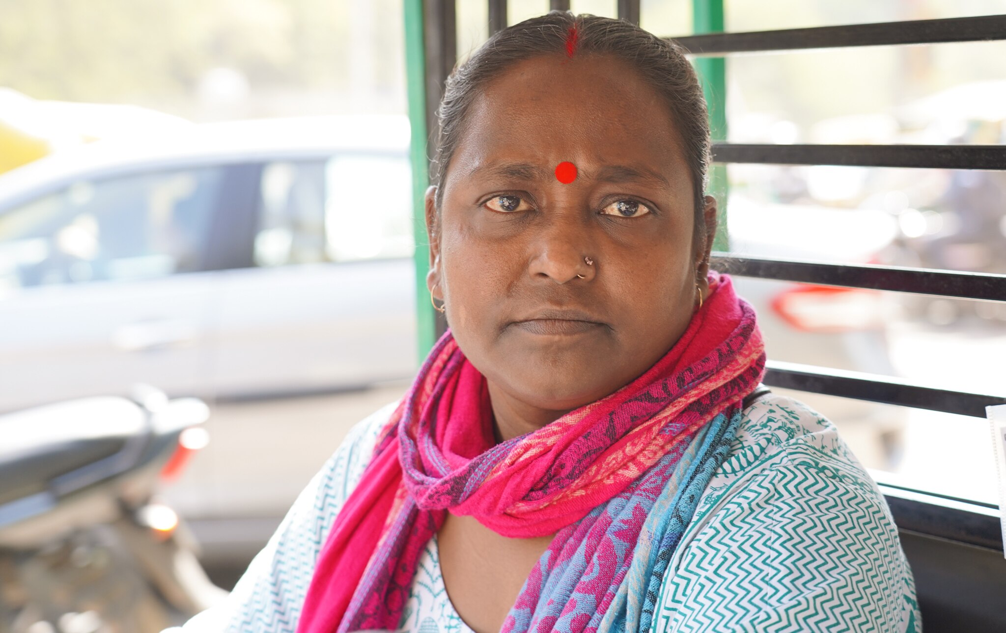 A close up of an Indian woman wearing a pink scarf and blue top with a bindi on her forehand