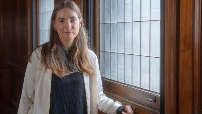 Evelyn Araluen stands next to a wooden window.