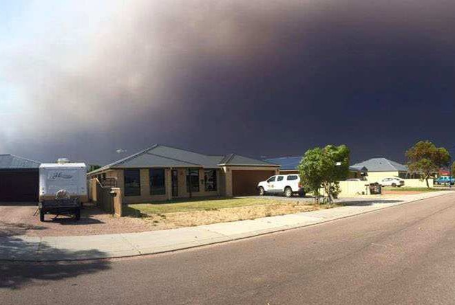 Smoke from a bushfire billows over houses in Cairns Parade in Le Grande estate in Esperance