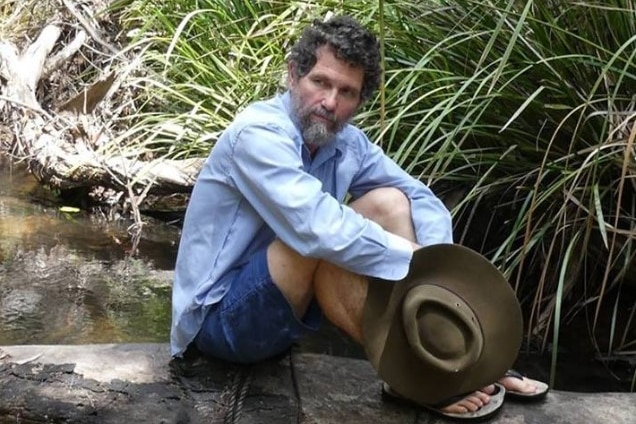 Peter Ridd sitting on a log above a bush creek