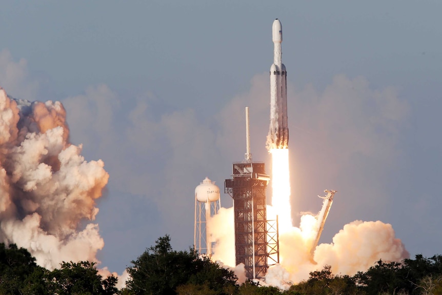 A rocket takes off from a launchpad with flames underneath.