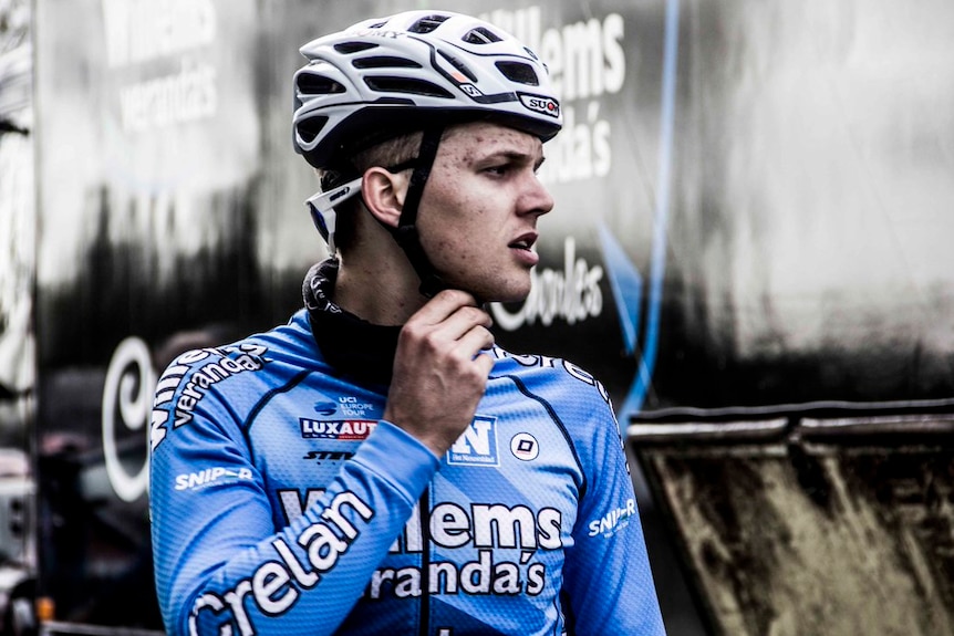 Image of a dirt-covered cyclist adjusting his helmet