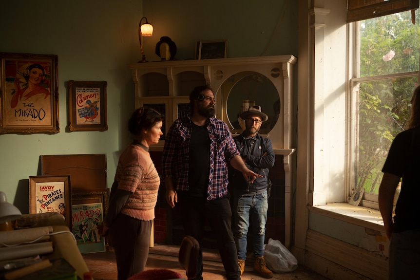 Director standing in the middle of two actors on a house set.
