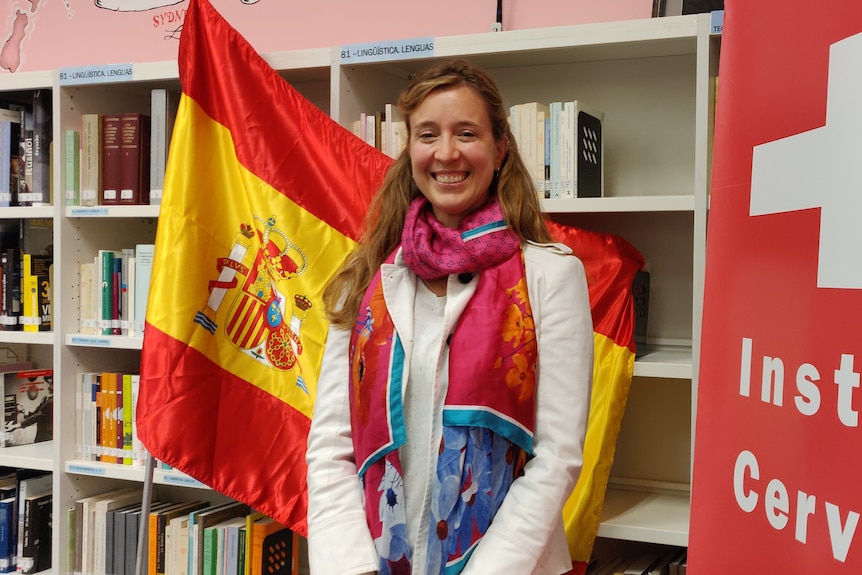 Женщина, стоящая с флагом Испании в библиотеке