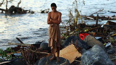 A man looks over the debris at the waterfront following an earthquake and tsunami in Samoa