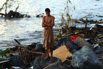 A man looks over the debris at the waterfront following an earthquake and tsunami in Samoa