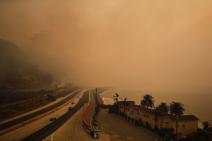 Traffic moves along the 101 Freeway as smoke from a wildfire fills the air in Ventura, California.