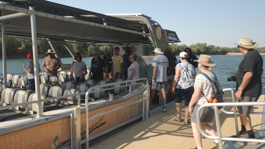 Tourists with hats and backpacks board a boat