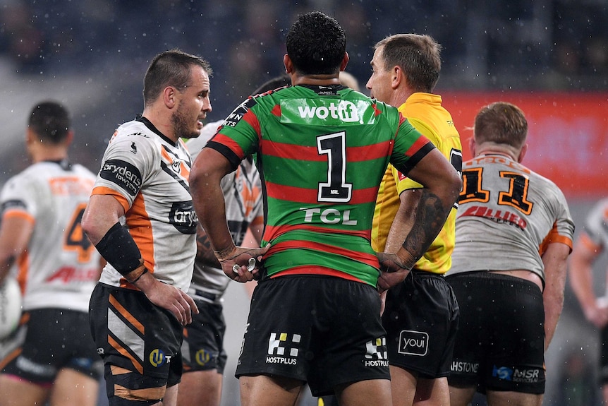 Latrell Mitchell is seen from behind as the referee speaks to Josh Reynolds (left) during the Rabbitohs-Tigers NRL game.