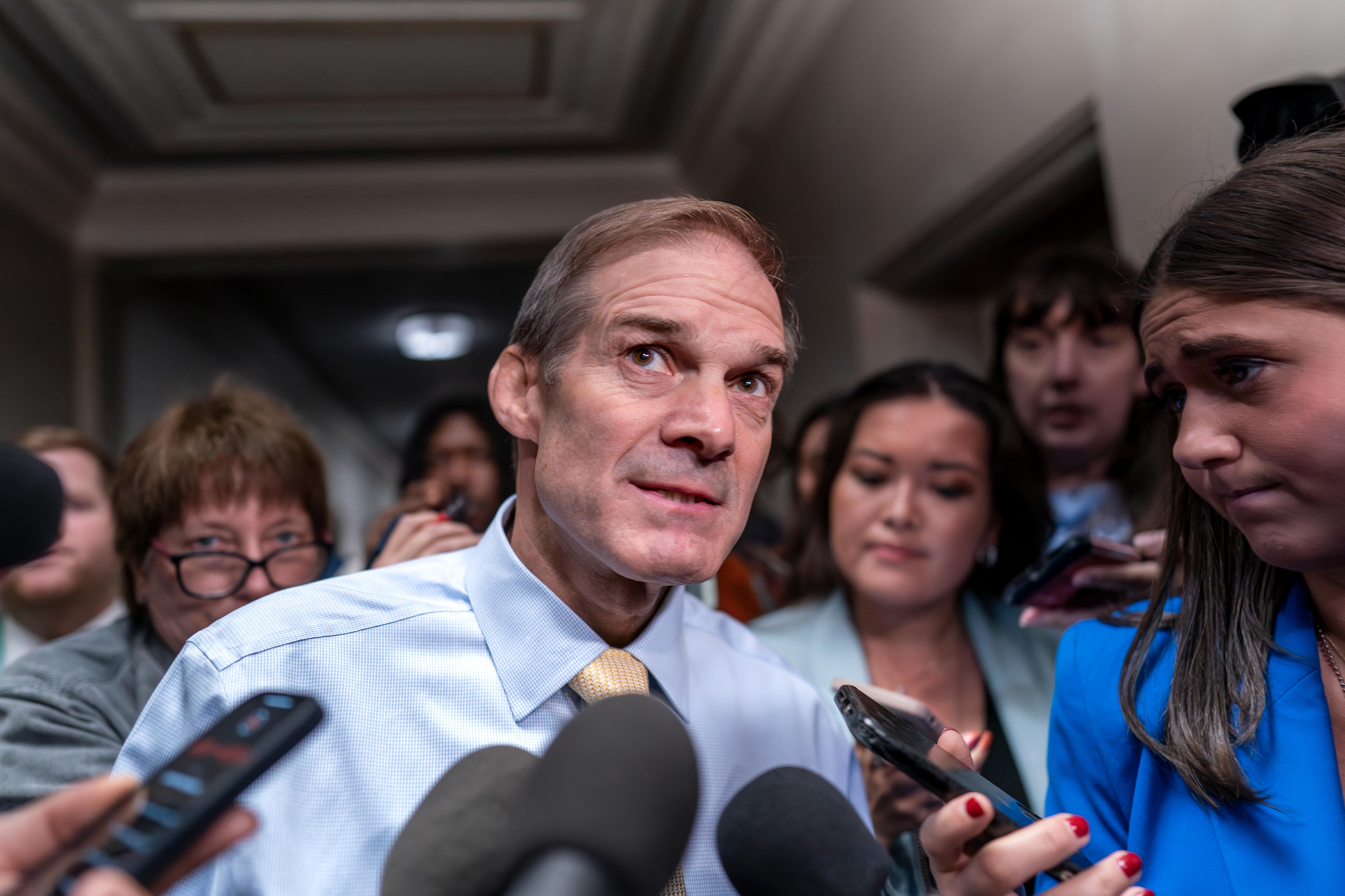 US representative Jim Jordan surrounded by journalists holding out phones and microphones
