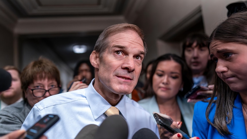 US representative Jim Jordan surrounded by journalists holding out phones and microphones