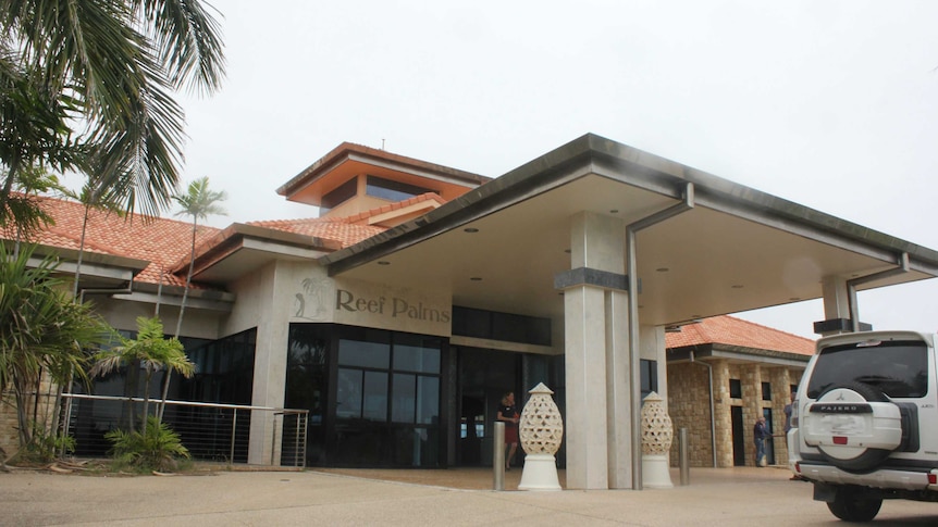 resort building with palm tree on left and four-wheel-drive on right