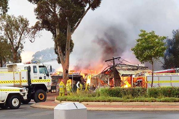 Fire engulfs a building in Kalgoorlie, with firefighters and fire trucks nearby.